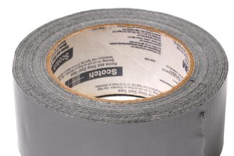 Egy tekercs szürke ragasztószalag, enyhén felemelt széllel, amelyen a Scotch márkajelzés látható a belső kartongyűrűn. A szalag textúrája látható, és a tekercs függőlegesen áll a fehér háttéren.